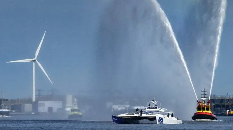 A futuristic catamaran sailing ship in Amsterdam harbour with fireboats spraying celebratory water