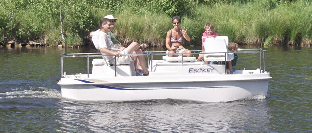 Electric poat going along a river with 4 people aboard enjoying themselves