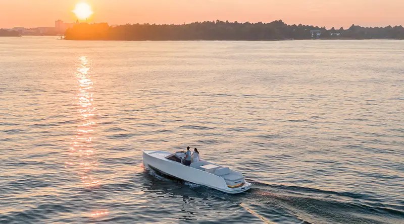 An electric yacht is on a lake at sunset