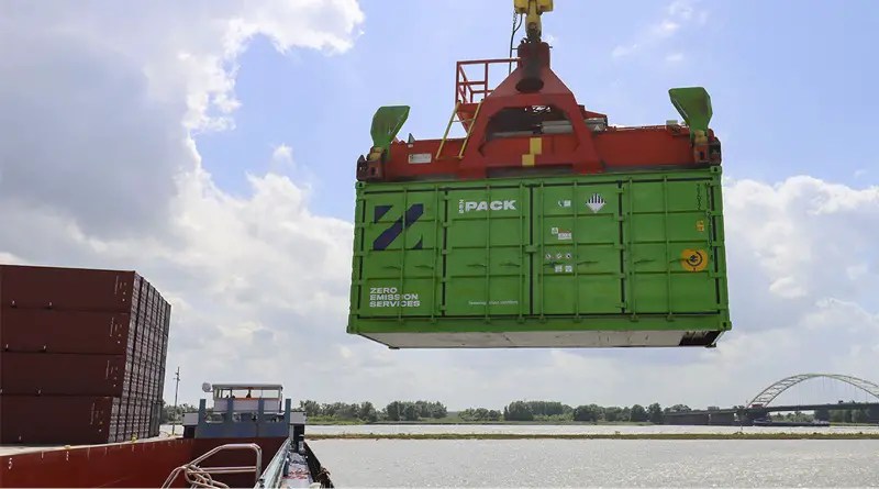 shipping container batteries being loaded by crane onto a barge