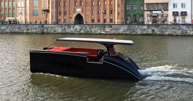 Dark blue electric solar boat driving along a canal