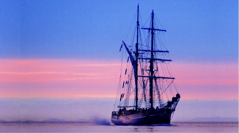 tall ship with electric motor sailing at beautiful sunset