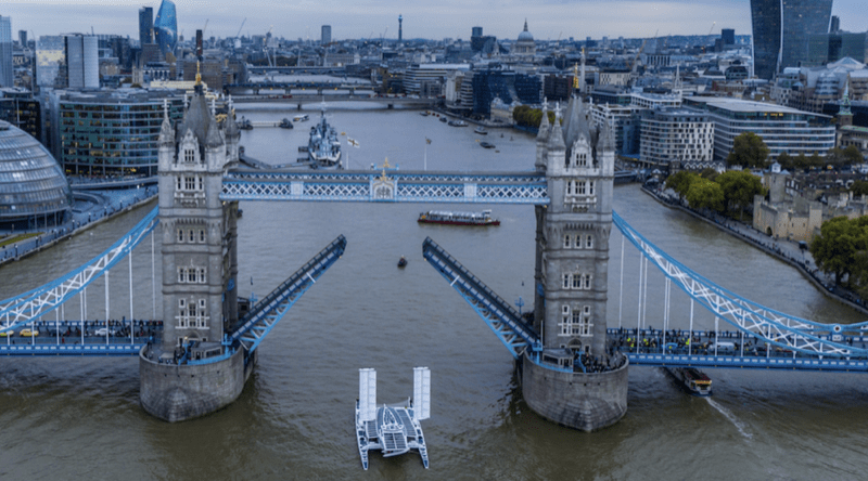 the Energy Observer zero emission ship sails under the raised drawbridge of London's Tower Bridge